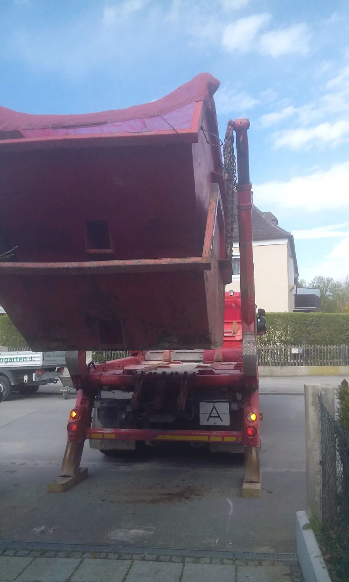 Kipplaster mit hochgefahrenem Mulden-Aufbau beim Abtransport von Aushubmaterial – Bodenentsorgung auf einer Baustelle im deutschen Wohngebiet
