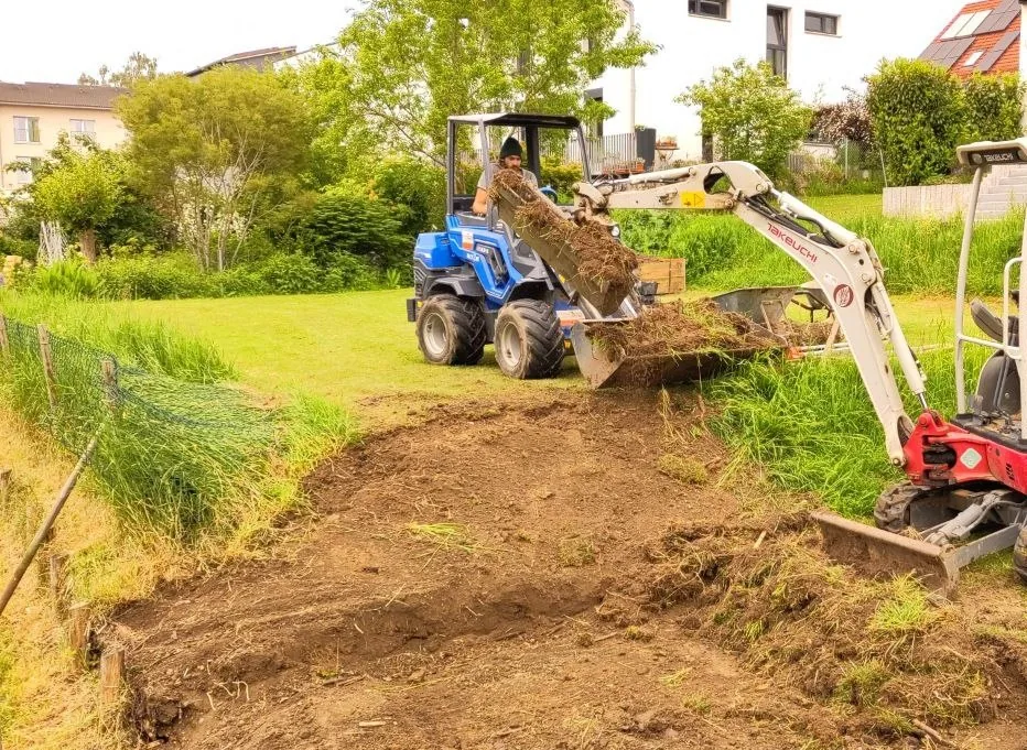 Bagger und Radlader beim Humusabtrag auf Gartenfläche – Oberboden wird abgezogen und verladen