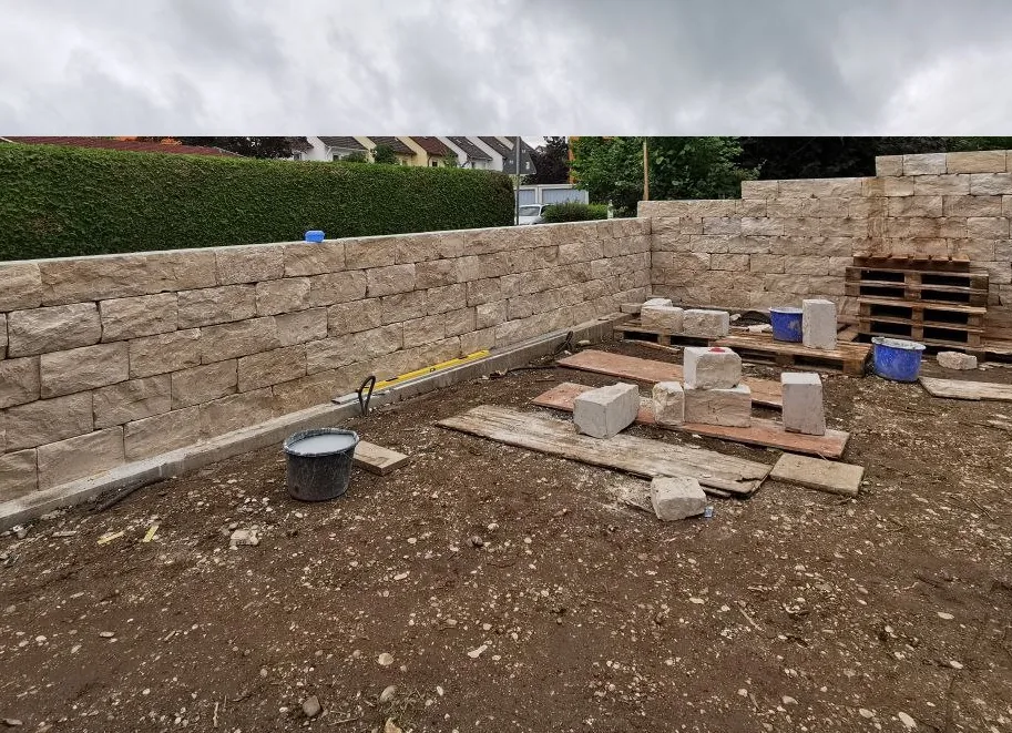 Gartenmauer im Aufbau aus Jurakalkstein – Steinlagen werden geschichtet, Fugen sichtbar, Gartenumgebung
