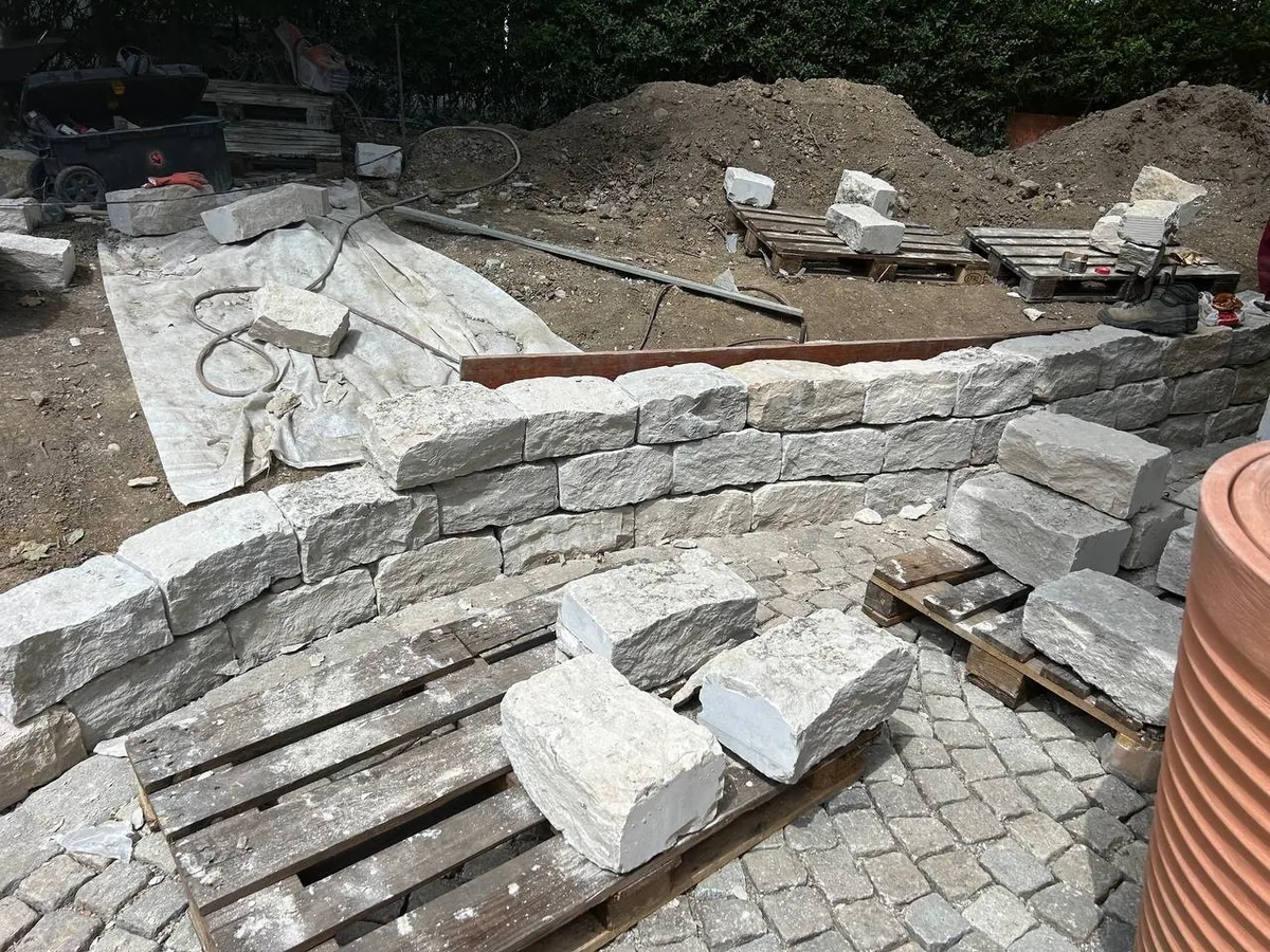 Gartenmauer aus Kalkstein im Selbstbau – Steinlagen werden gesetzt, sorgfältige Ausrichtung mit Richtschnur