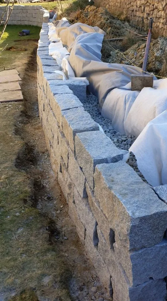 Granit-Stützmauer im Aufbau – Steine werden gesetzt, Geländeabfangung im Entstehen, Baugarten