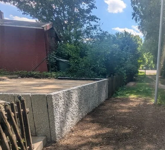 Stützmauer aus Granit-Stelen – aufrecht gestellte Granitblöcke als moderne Stützmauerlösung im Garten