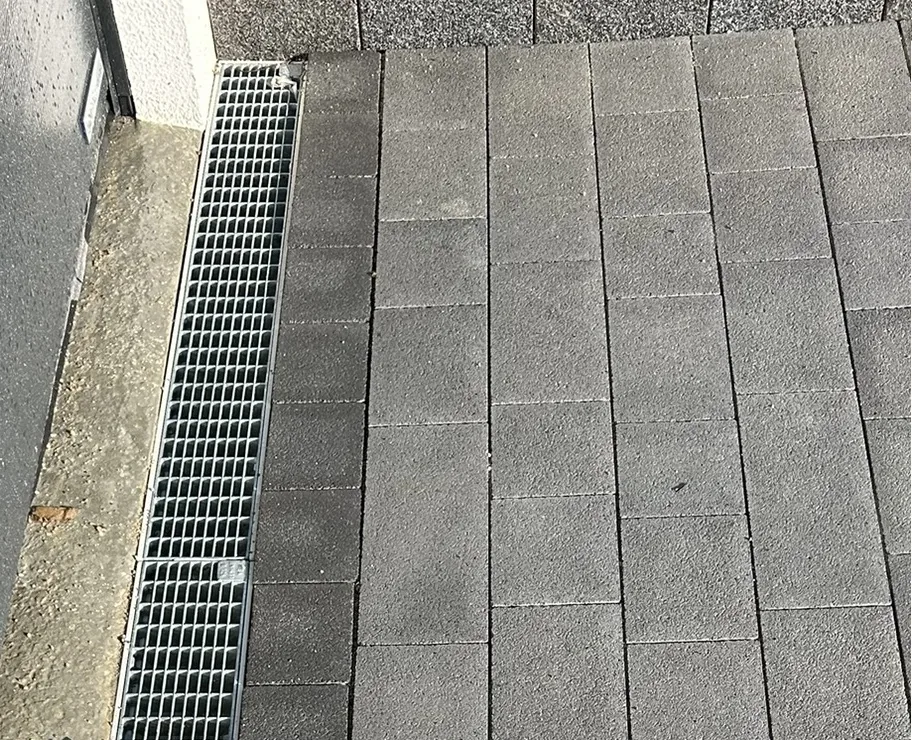 Entwässerungsrinne mit Gitterrost quer in Einfahrt eingebaut – Querrinne zur Wasserabführung vor Garage