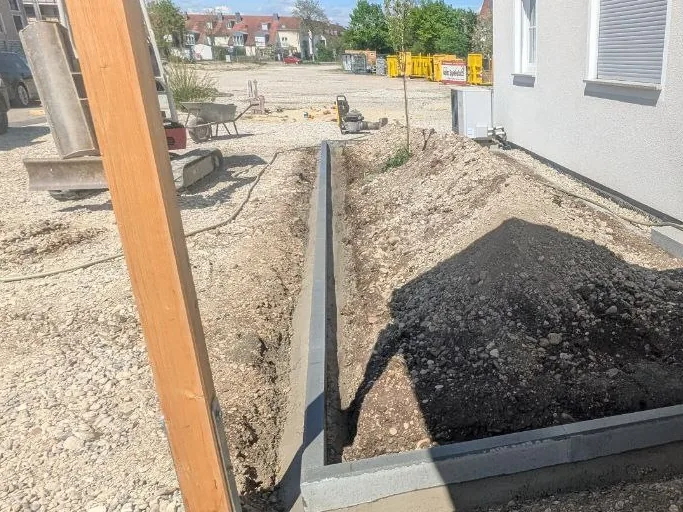 Tiefbordstein wird gesetzt – Betonbordstein auf Betonbett in Einfahrtsbereich
