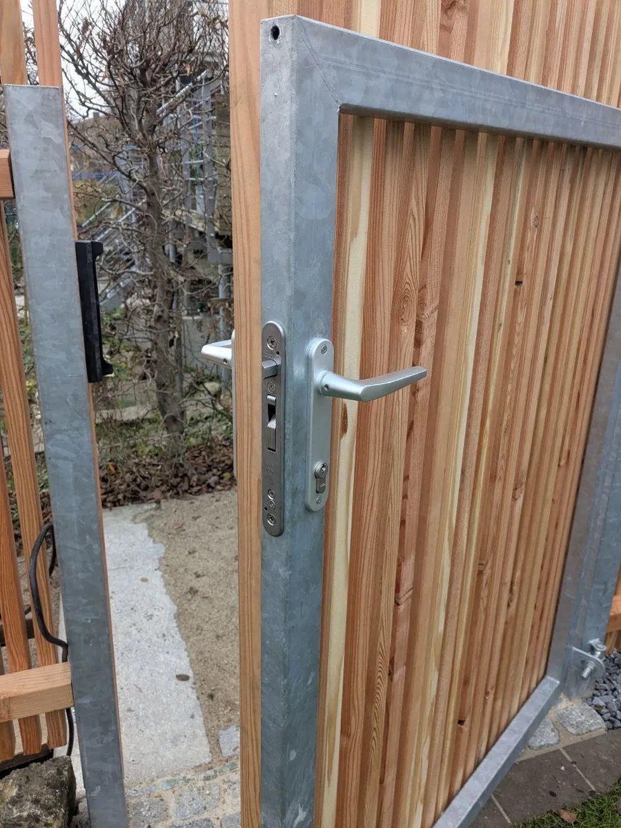 Holzzaun mit Gartentür in Metallrahmen – Tür montiert in offenstehender Position, passendes System zum Zaun